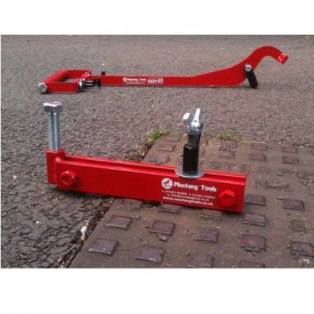 Red steel Mustang mini seal breaker on a manhole cover with the Mustang eazy lift in the background