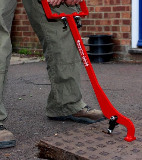 Man using the red steel eazy lift manhole cover lifter to lift a metal manhole cover