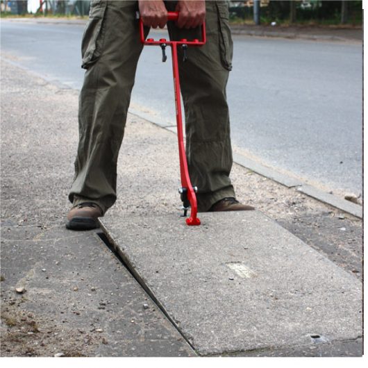 Man using the red steel eazy lift manhole cover lifter to lift a manhole cover