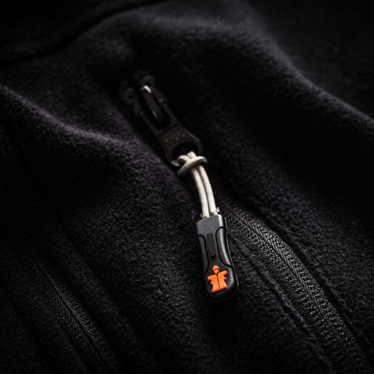 Close up of black pocket zip with orange Scruffs logo on the end of the zip, on the worker fleece