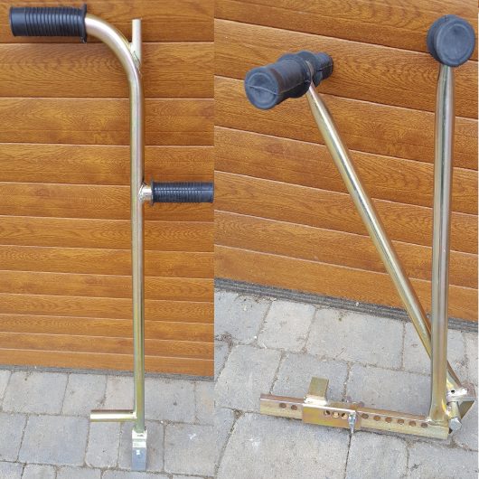 Galvanised metal block paving gap wedge and block lifter with black rubber handles leaning against a wall