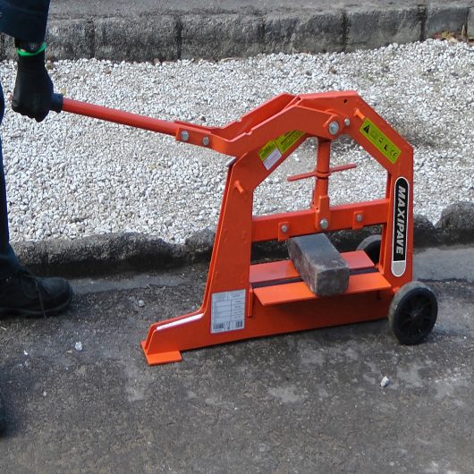 Worker using the orange metal Belle maxipave block cutter to cut blocks