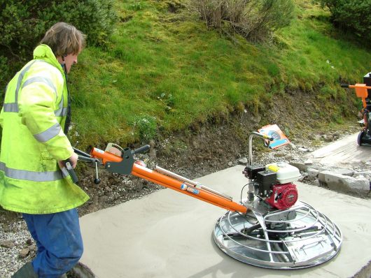 Worker wearing protective clothing whilst using the Belle pro tilt trowel on some concrete